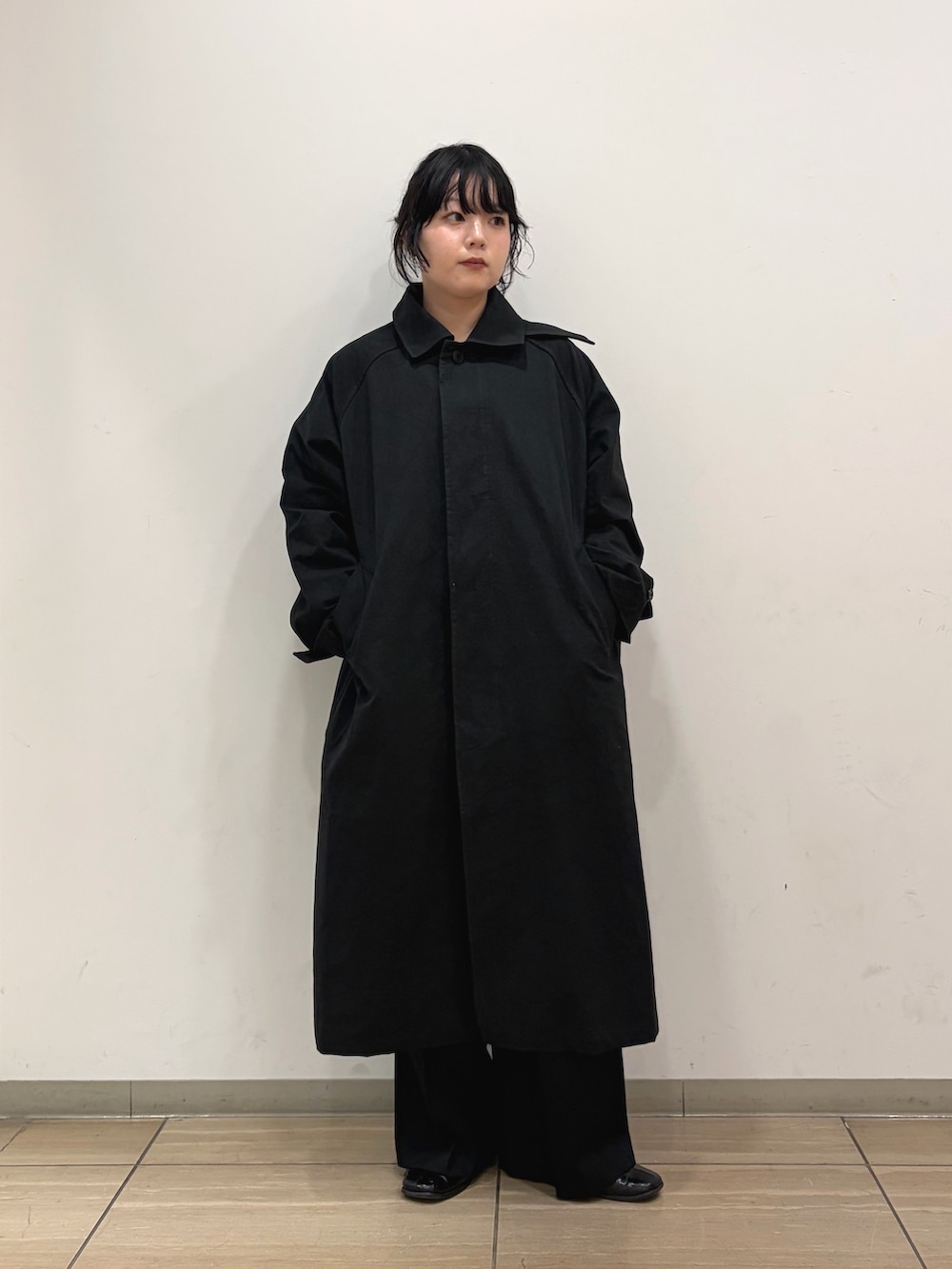 ブラック系のステンカラーコート、イエロー系のニット/セーター、ブラック系のその他パンツを着用したレディースの冬コーディネートの3枚目の写真