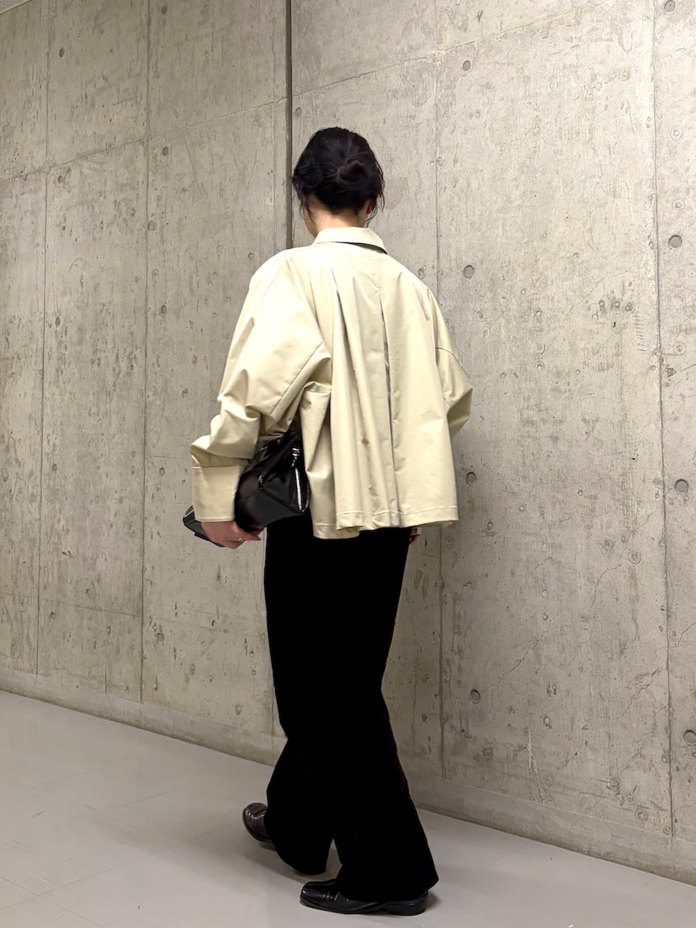 グレー系のステンカラーコート、ブラック系のデニムパンツ、ブラック系のボストンバッグを着用したレディースの冬コーディネートの2枚目の写真