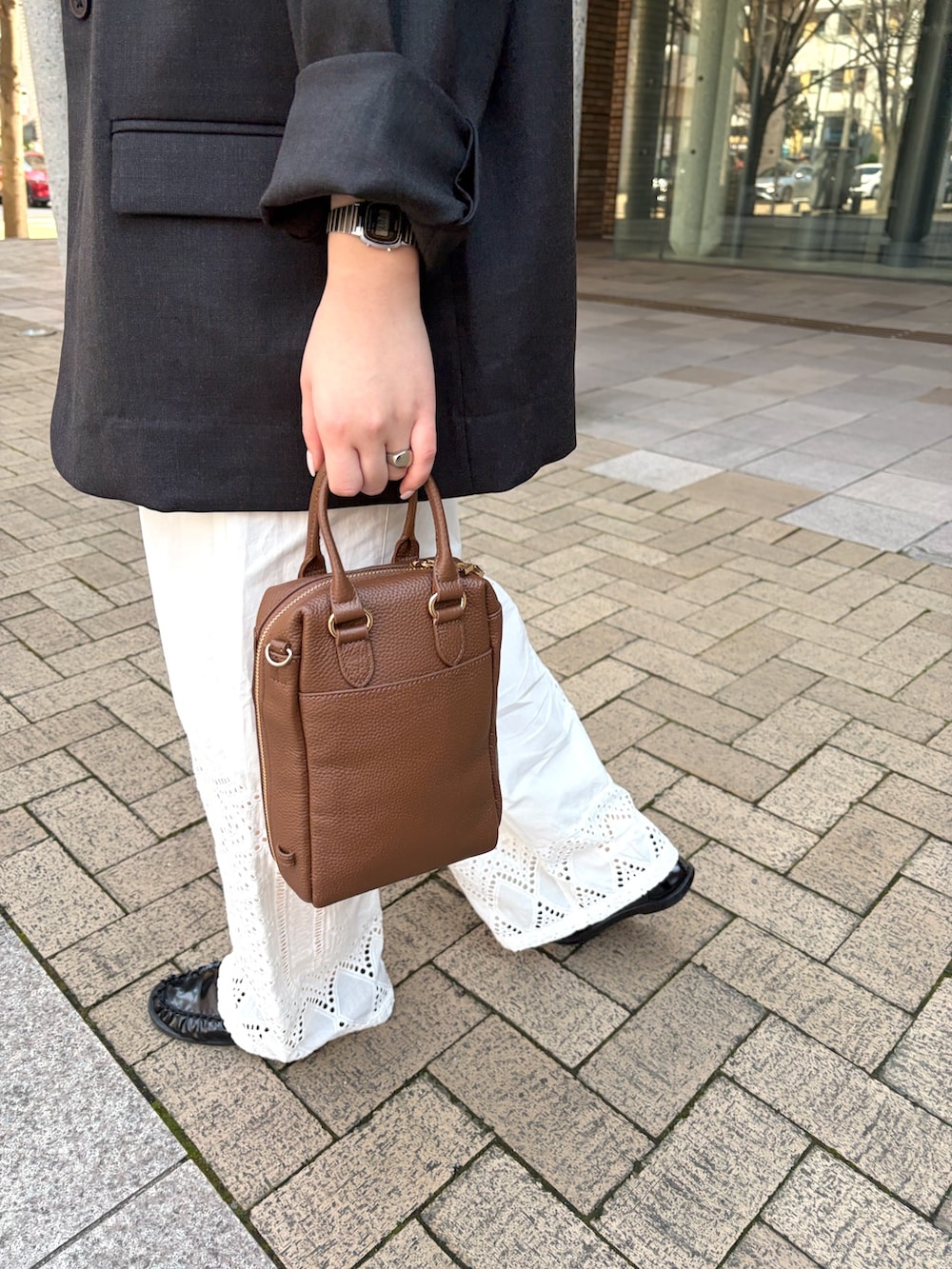 グレー系のその他アウター、ホワイト系のその他パンツ、ブラウン系のボストンバッグを着用したレディースの春コーディネートの3枚目の写真