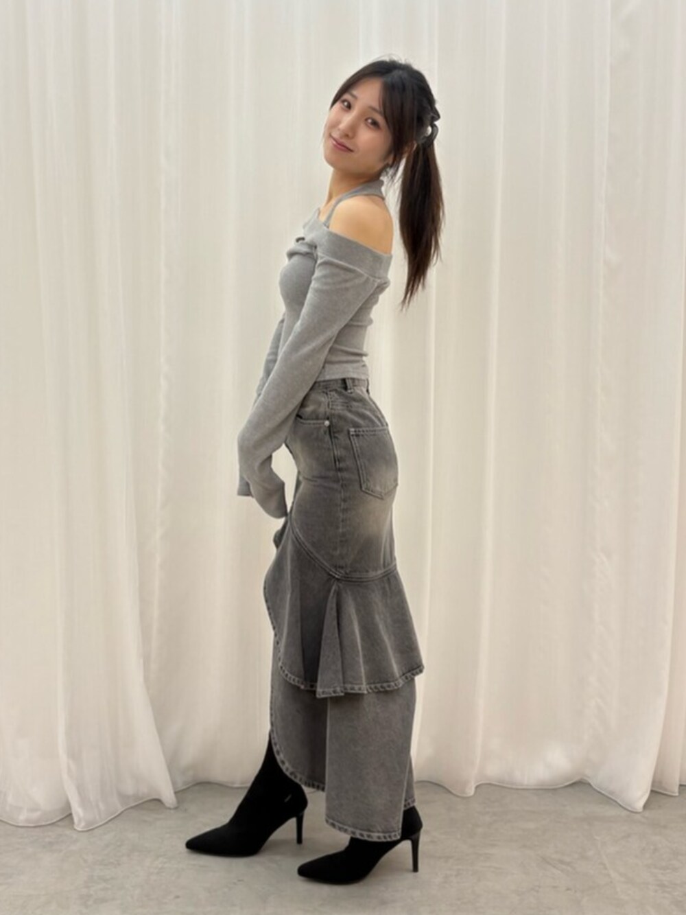 ブラック系のデニムスカート、グレー系のTシャツ/カットソー、ブラック系のブーツを着用したレディースの秋コーディネートの2枚目の写真