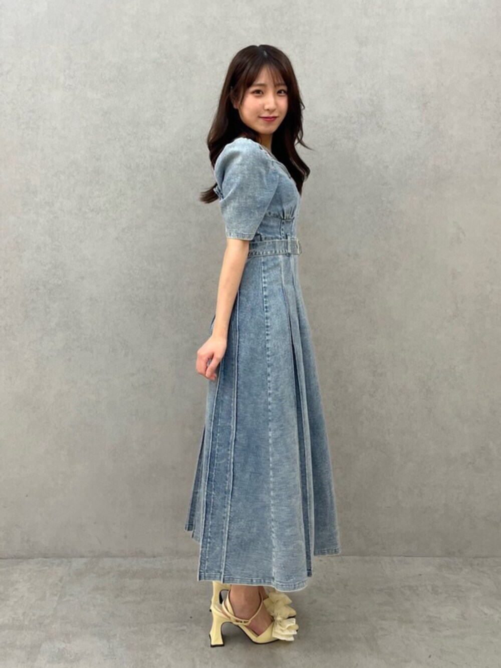 ブルー系のワンピース、イエロー系のパンプスを着用したレディースの春コーディネートの2枚目の写真