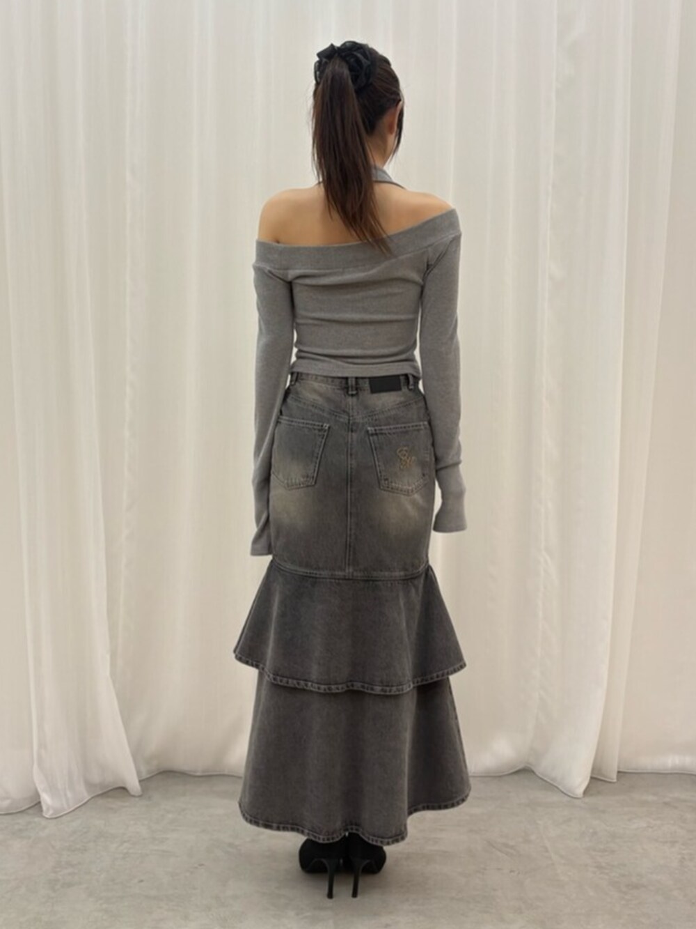 ブラック系のデニムスカート、グレー系のTシャツ/カットソー、ブラック系のブーツを着用したレディースの秋コーディネートの3枚目の写真