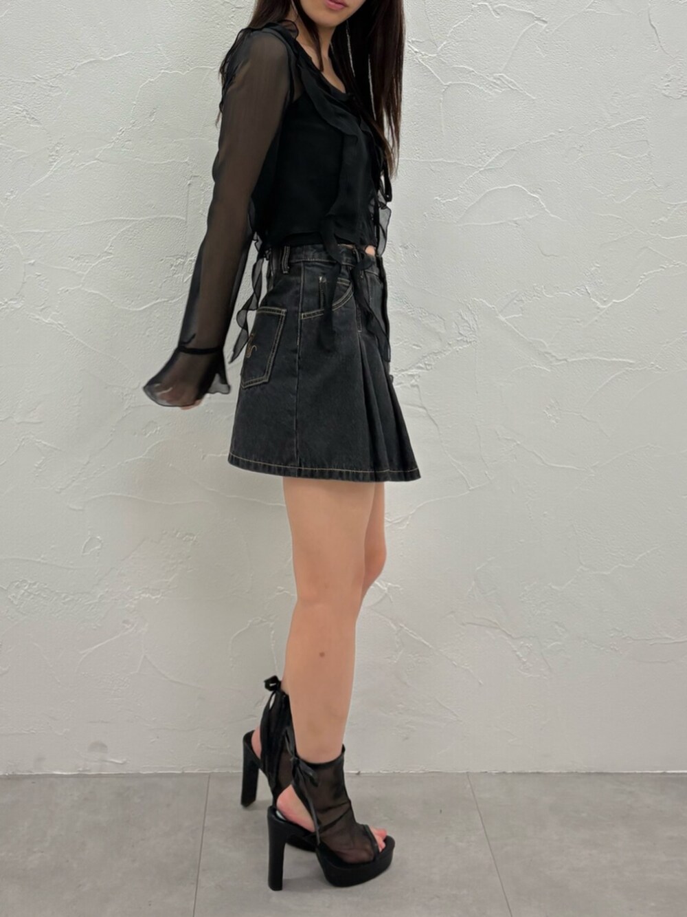 ブラック系のデニムスカート、ブラック系のカーディガン/ボレロ、ブラック系のキャミソールを着用したレディースの夏コーディネートの3枚目の写真