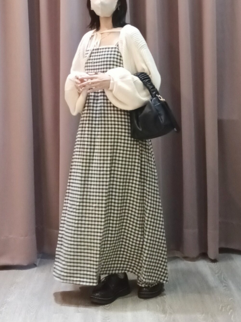 ブラック系のハンドバッグ、ブラウン系のシューズ、ホワイト系のカーディガン/ボレロを着用したレディースの秋コーディネートの2枚目の写真