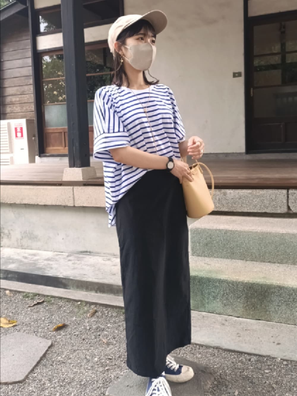 ブルー系のTシャツ/カットソー、イエロー系のドラムバッグ、ブラック系のスカートを着用したレディースの春コーディネートの2枚目の写真