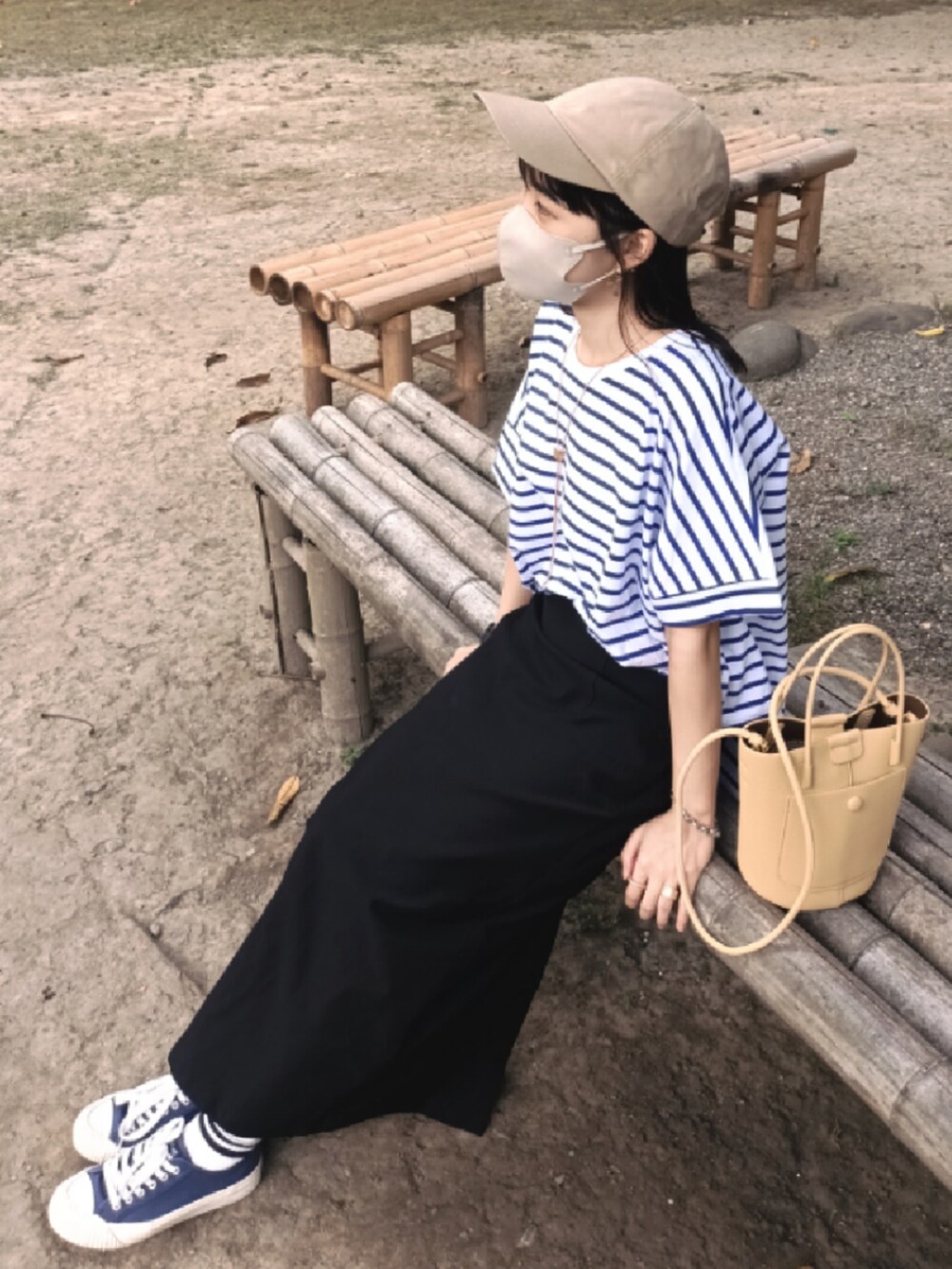 ブルー系のTシャツ/カットソー、イエロー系のドラムバッグ、ブラック系のスカートを着用したレディースの春コーディネートの3枚目の写真