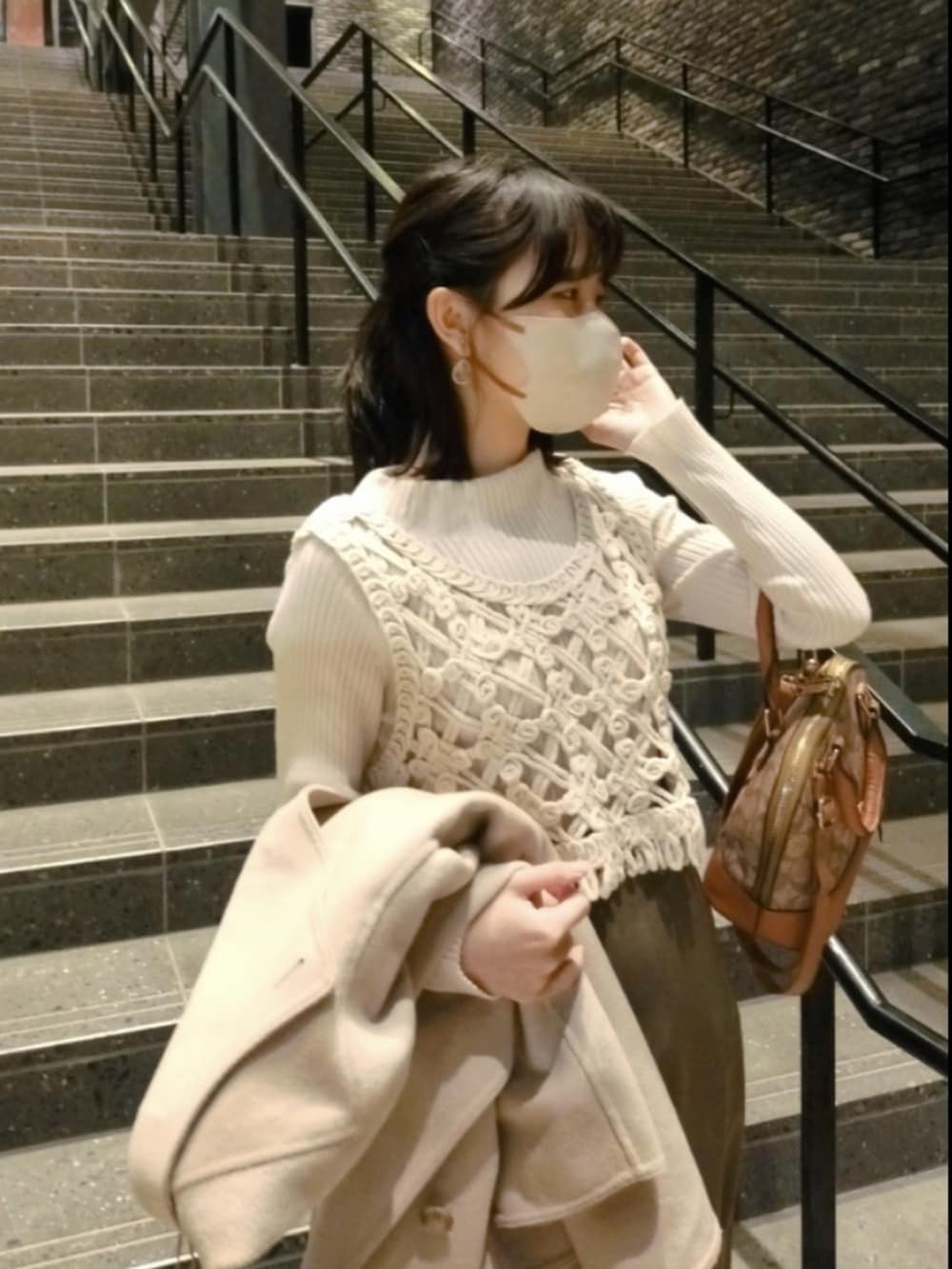 ブラウン系のボストンバッグ、ベージュ系のダッフルコート、ブラウン系のスカートを着用したレディースの春コーディネートの2枚目の写真