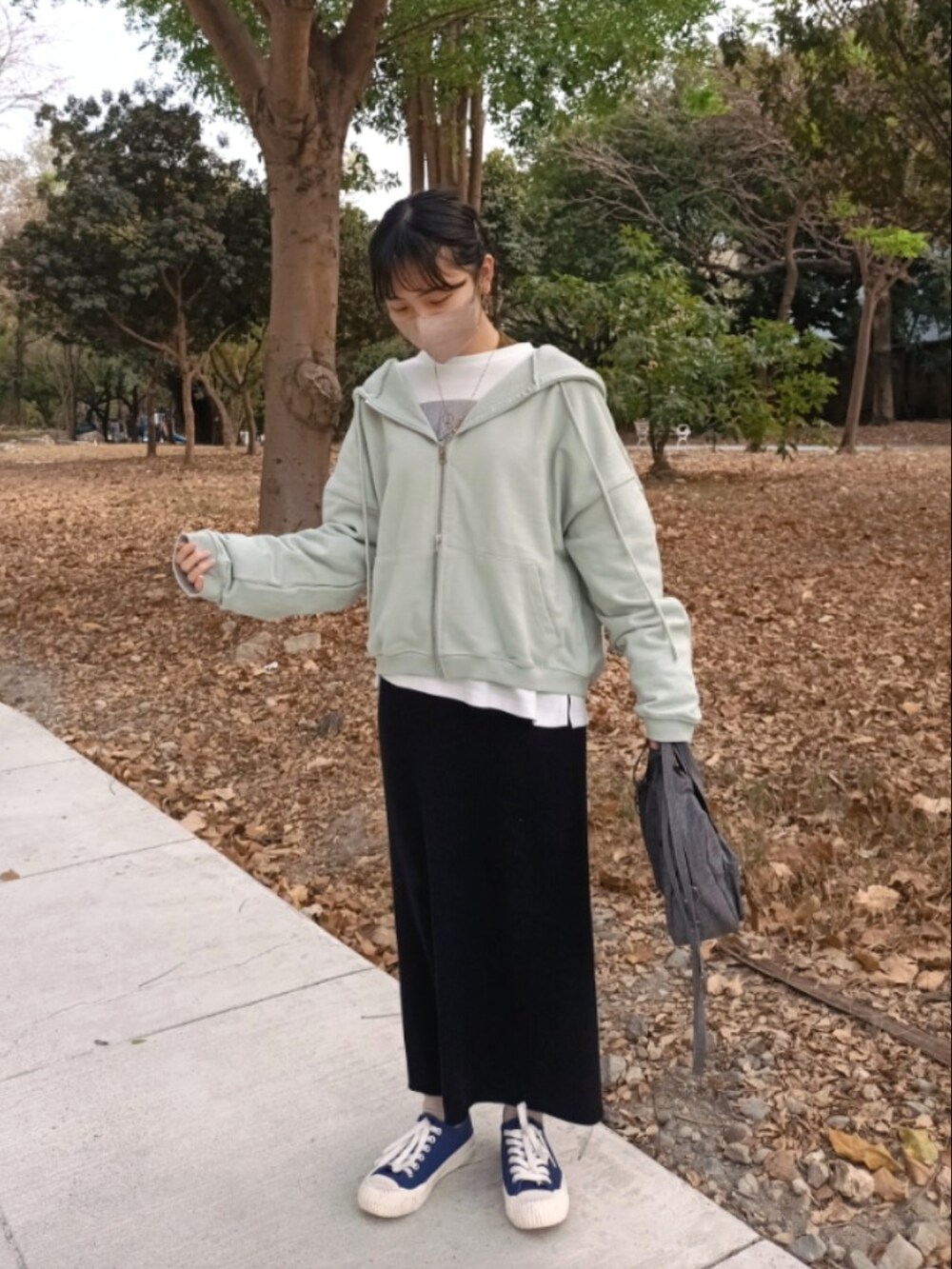 ブラック系のスカート、ホワイト系のTシャツ/カットソー、グリーン系のパーカーを着用したレディースの春コーディネートの2枚目の写真