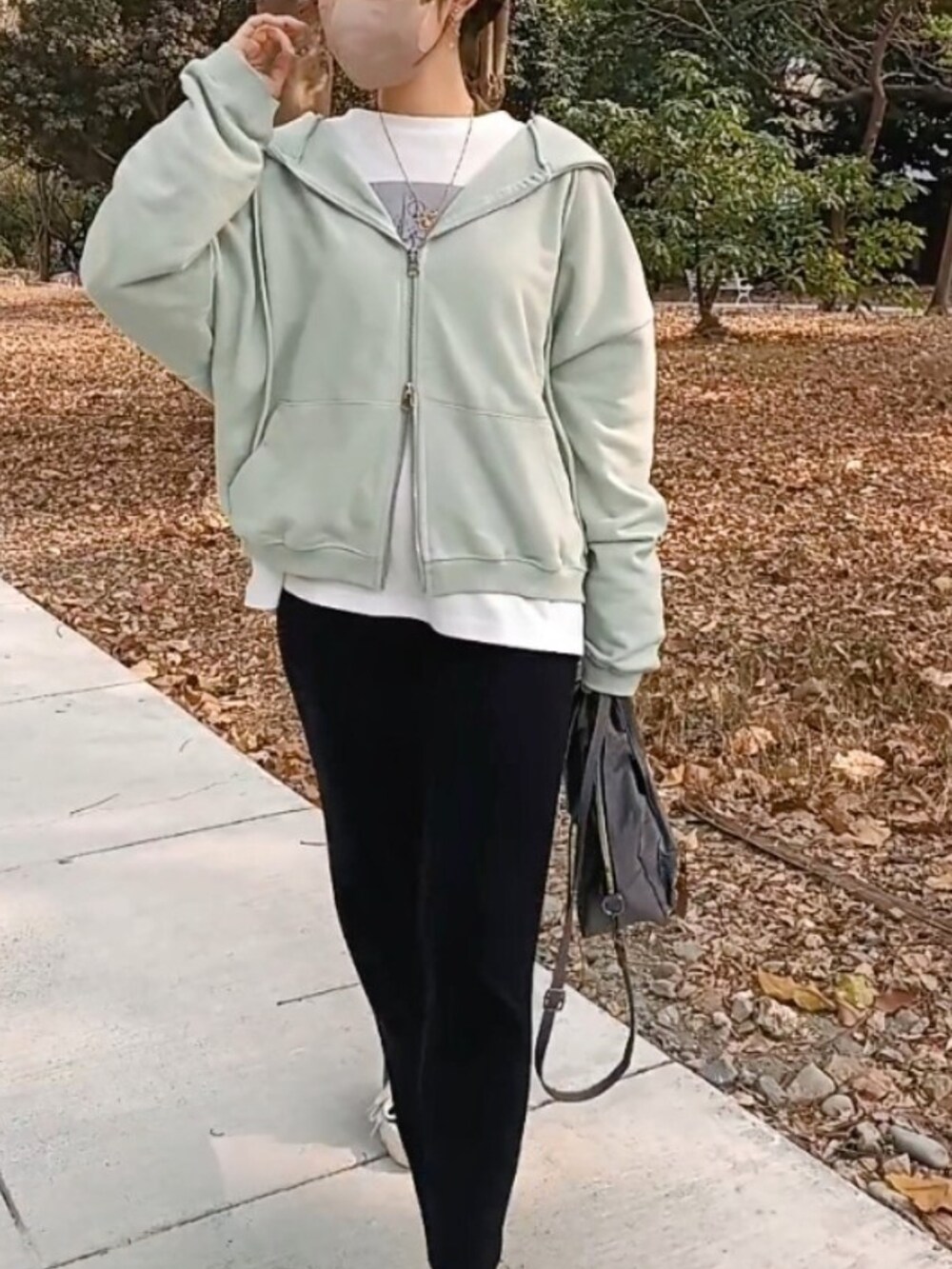 ブラック系のスカート、ホワイト系のTシャツ/カットソー、グリーン系のパーカーを着用したレディースの春コーディネートの3枚目の写真