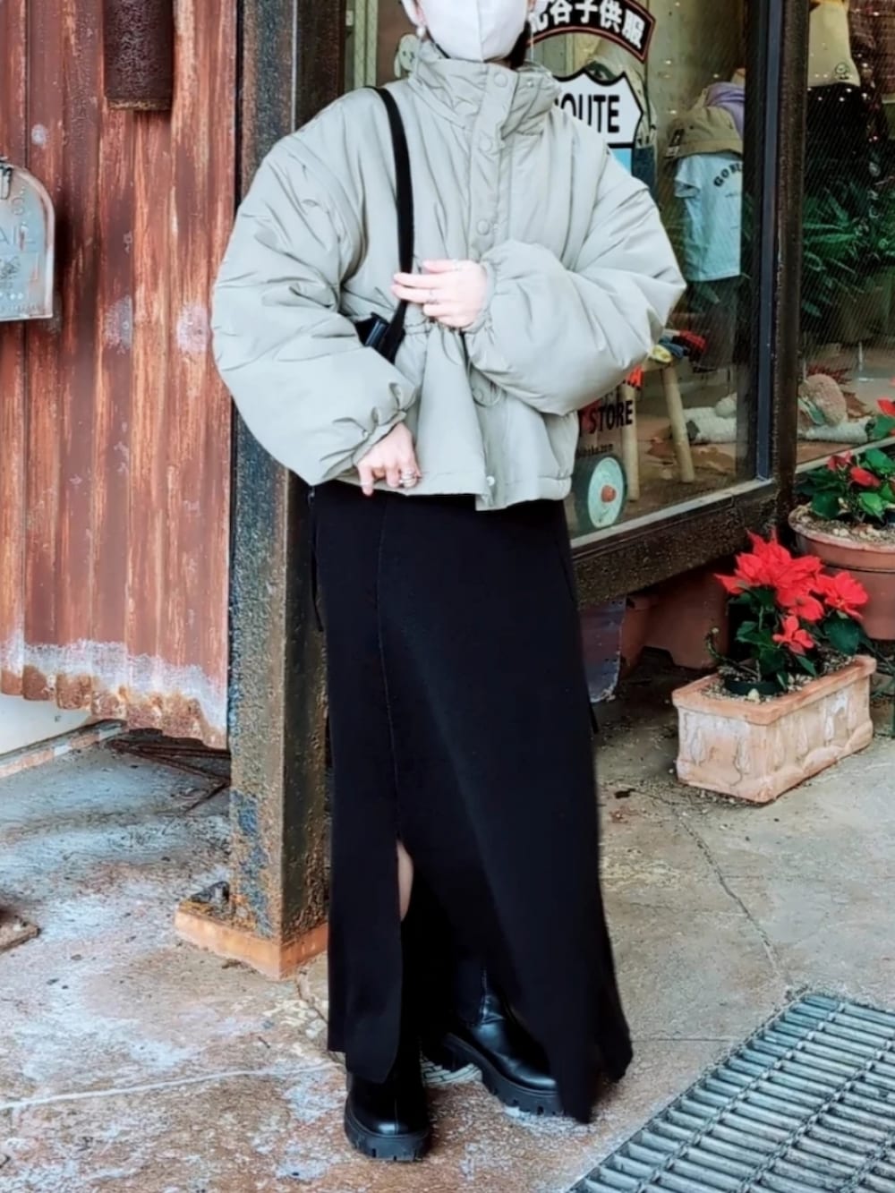 グリーン系のダウンジャケット/コート、ブラック系のワンピース、ブラック系のブーツを着用したレディースの冬コーディネートの3枚目の写真