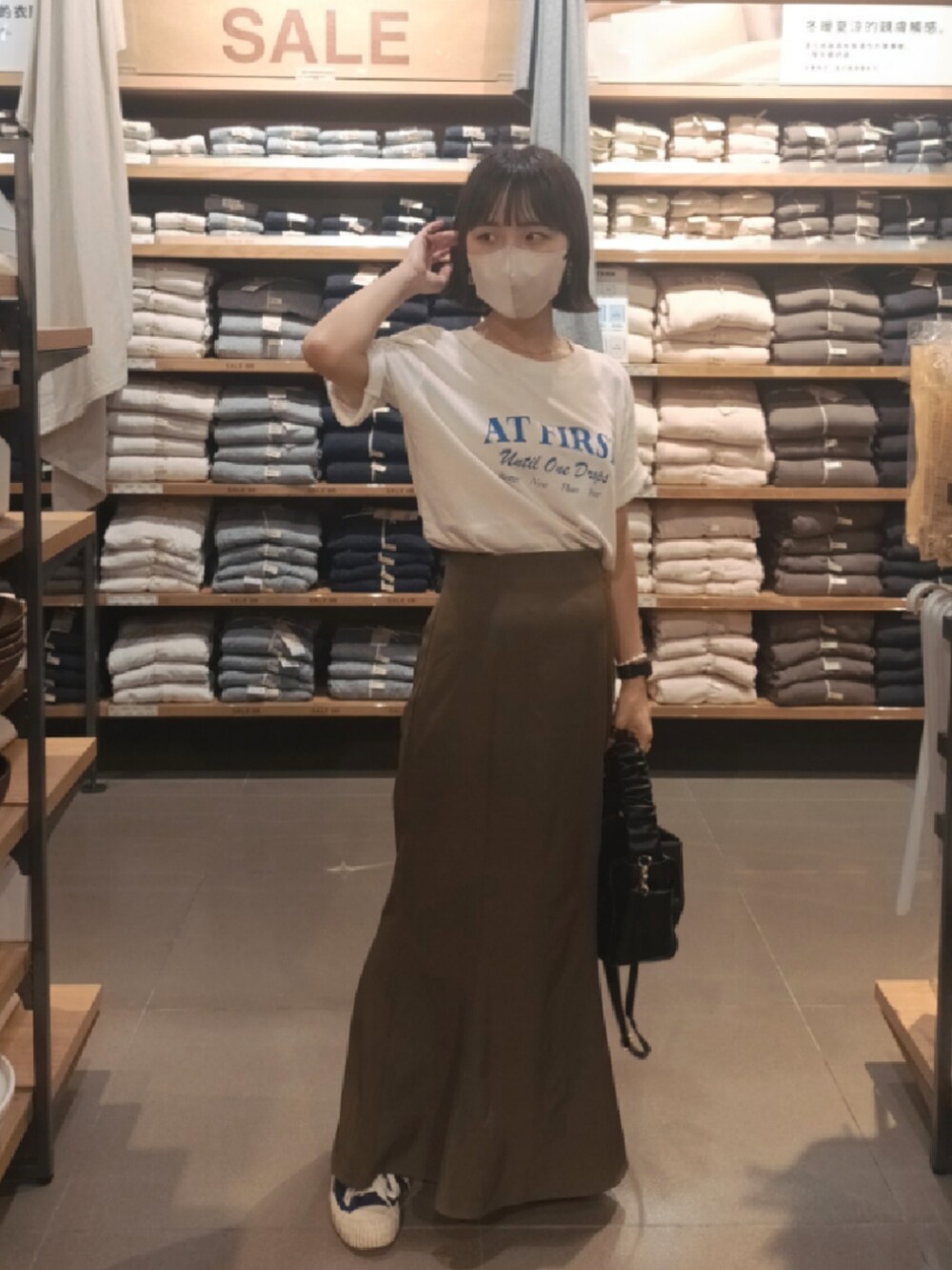 ブルー系のTシャツ/カットソー、ブラック系のハンドバッグ、ブラウン系のスカートを着用したレディースの夏コーディネートの2枚目の写真