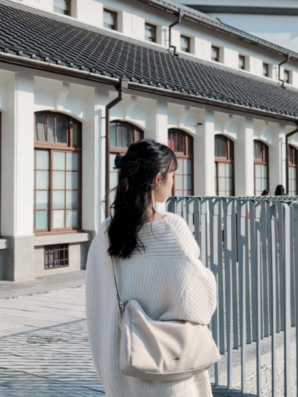 ブラック系のバレエシューズ、ホワイト系のボストンバッグ、ホワイト系のワンピースを着用したレディースの春コーディネートの2枚目の写真