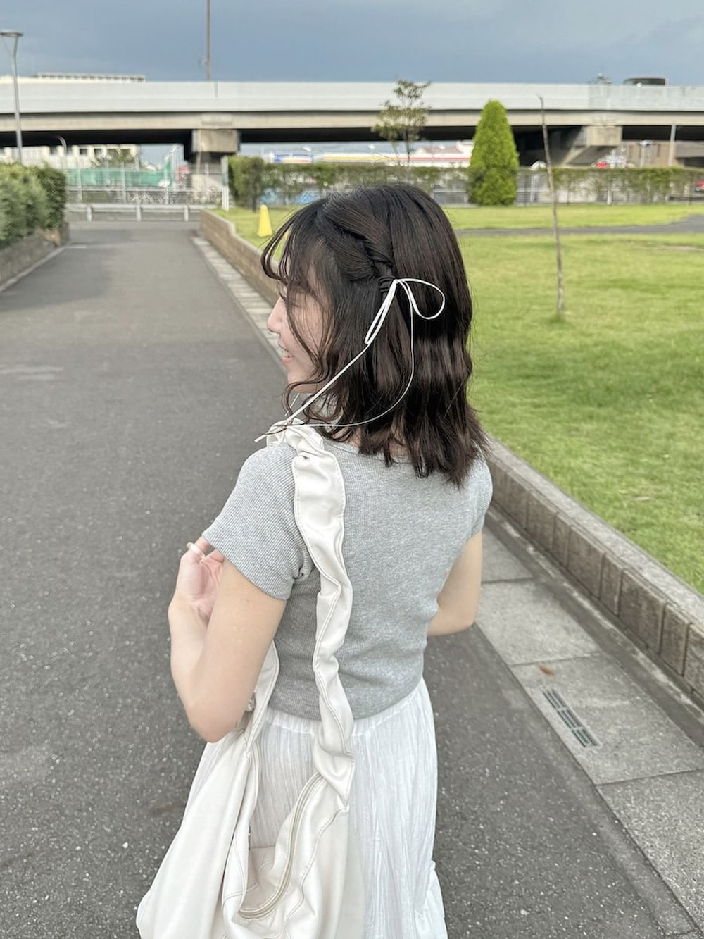ホワイト系のスカート、グレー系のTシャツ/カットソー、ホワイト系のバッグを着用したレディースの夏コーディネートの2枚目の写真