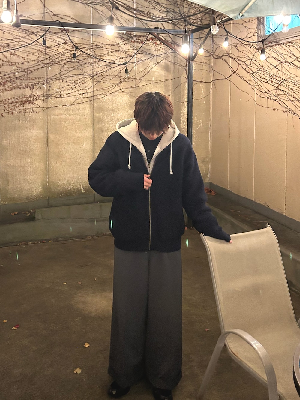 グレー系のスラックス、ブルー系のニット/セーター、グレー系のパーカーを着用したメンズの冬コーディネートの2枚目の写真