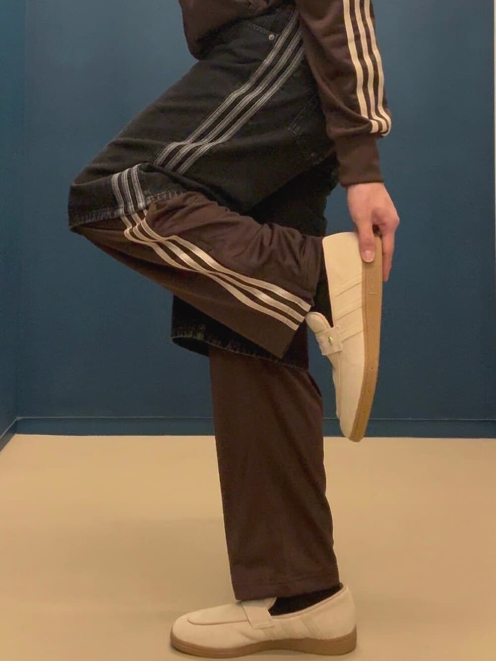 ベージュ系のスニーカー、ブラック系のデニムパンツ、ブラウン系のジャージを着用したメンズの春コーディネートの2枚目の写真