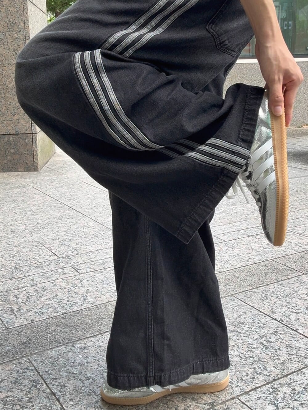 ブラック系のデニムパンツ、ブラック系のブルゾン、シルバー系のスニーカーを着用したメンズの秋コーディネートの4枚目の写真