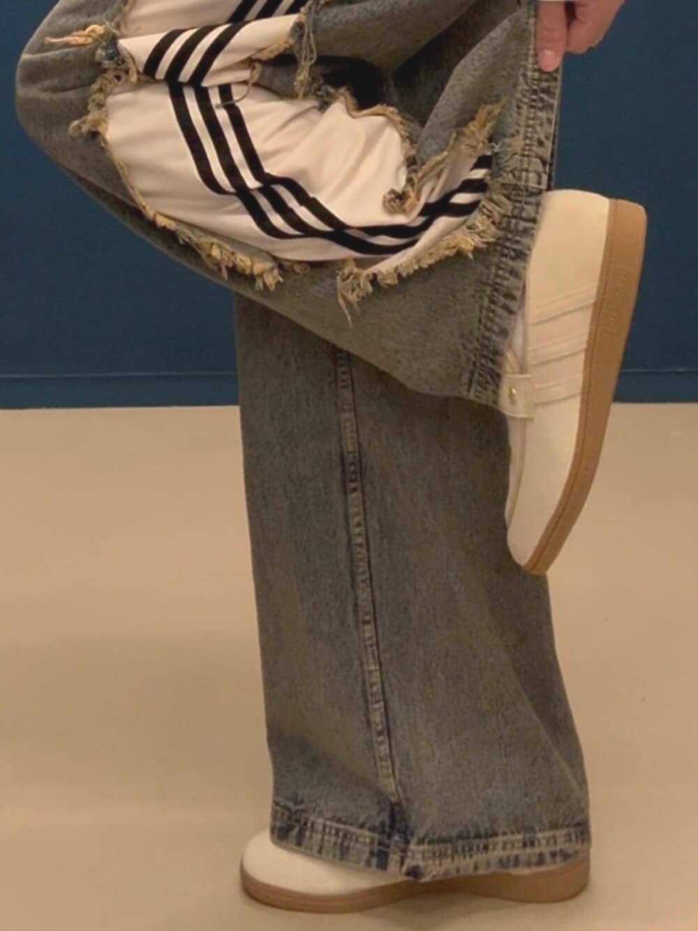 ベージュ系のスニーカー、レッド系のジャージ、ブラウン系のデニムパンツを着用したメンズの春コーディネートの2枚目の写真