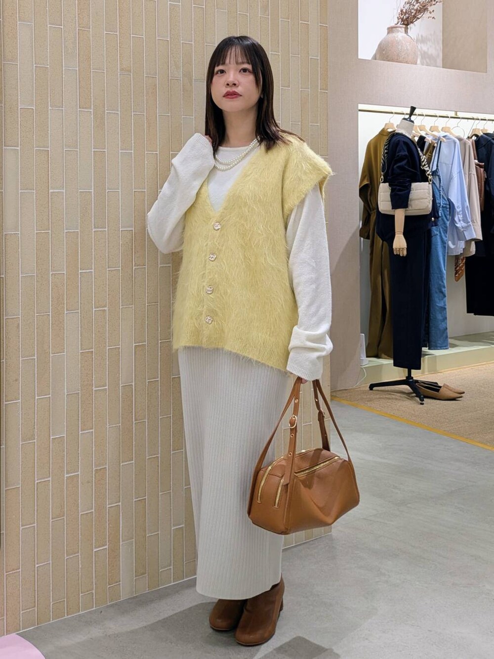 ベージュ系のスカート、ブラウン系のブーツ、ブラウン系のショルダーバッグを着用したレディースの秋コーディネートの2枚目の写真