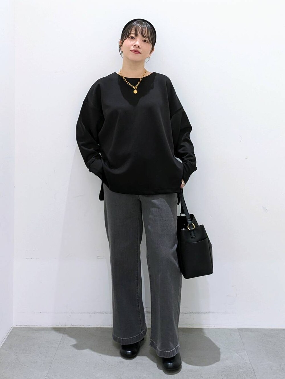 ブラック系のブーツ、ブラック系のショルダーバッグ、ブラック系のデニムパンツを着用したレディースの秋コーディネートの2枚目の写真