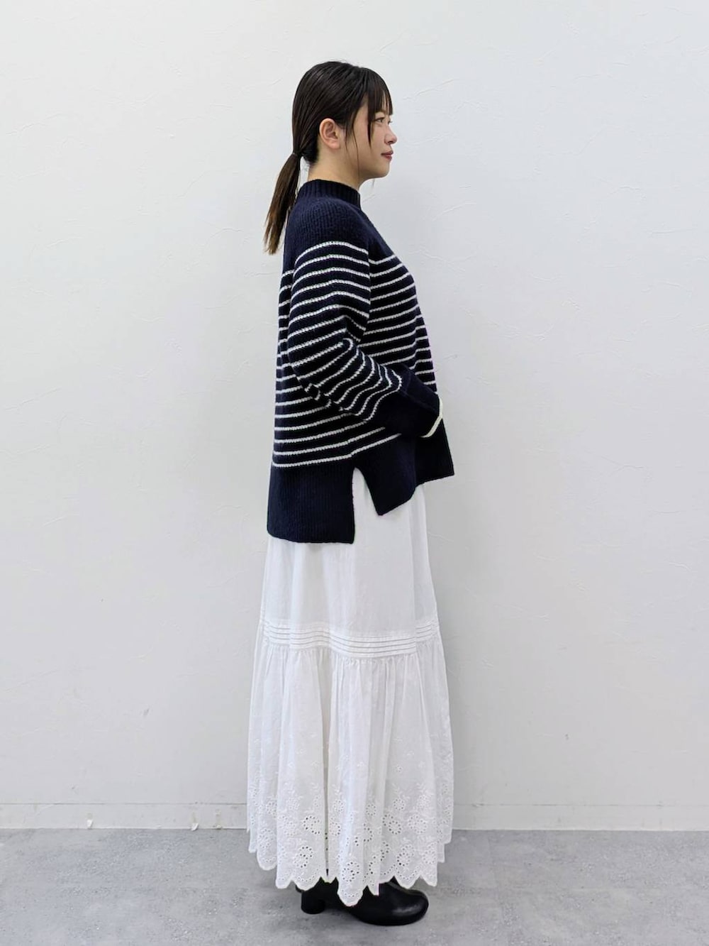 ブラック系のブーツ、ブルー系のニット/セーター、ホワイト系のスカートを着用したレディースの冬コーディネートの5枚目の写真