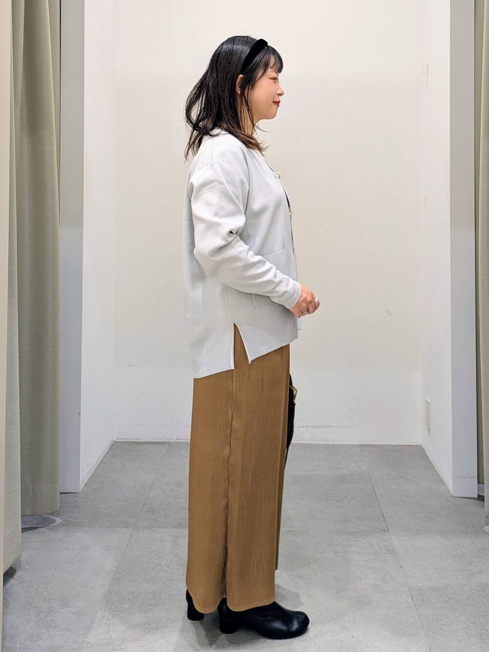 グレー系のカーディガン/ボレロ、ホワイト系のTシャツ/カットソー、ブラック系のブーツを着用したレディースの秋コーディネートの5枚目の写真