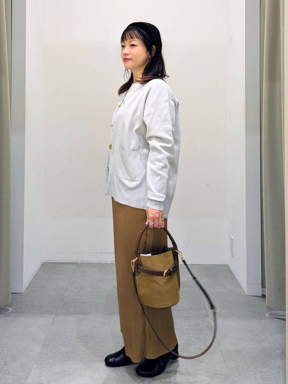 グレー系のカーディガン/ボレロ、ホワイト系のTシャツ/カットソー、ブラック系のブーツを着用したレディースの秋コーディネートの3枚目の写真