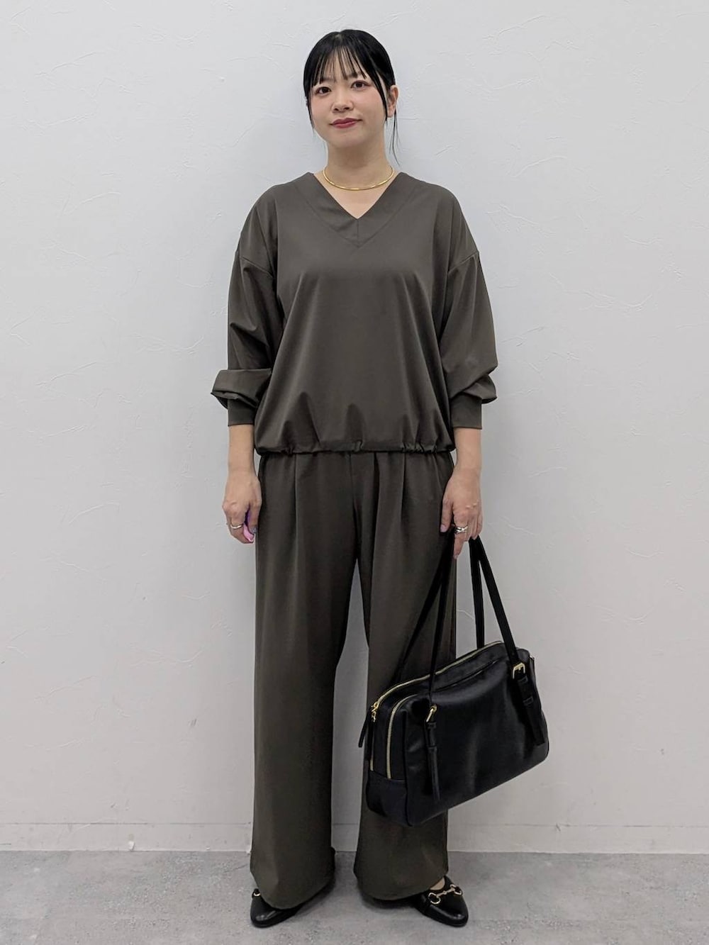 ブラック系のボストンバッグ、ブラック系のパンプス、グリーン系のその他パンツを着用したレディースの冬コーディネートの2枚目の写真