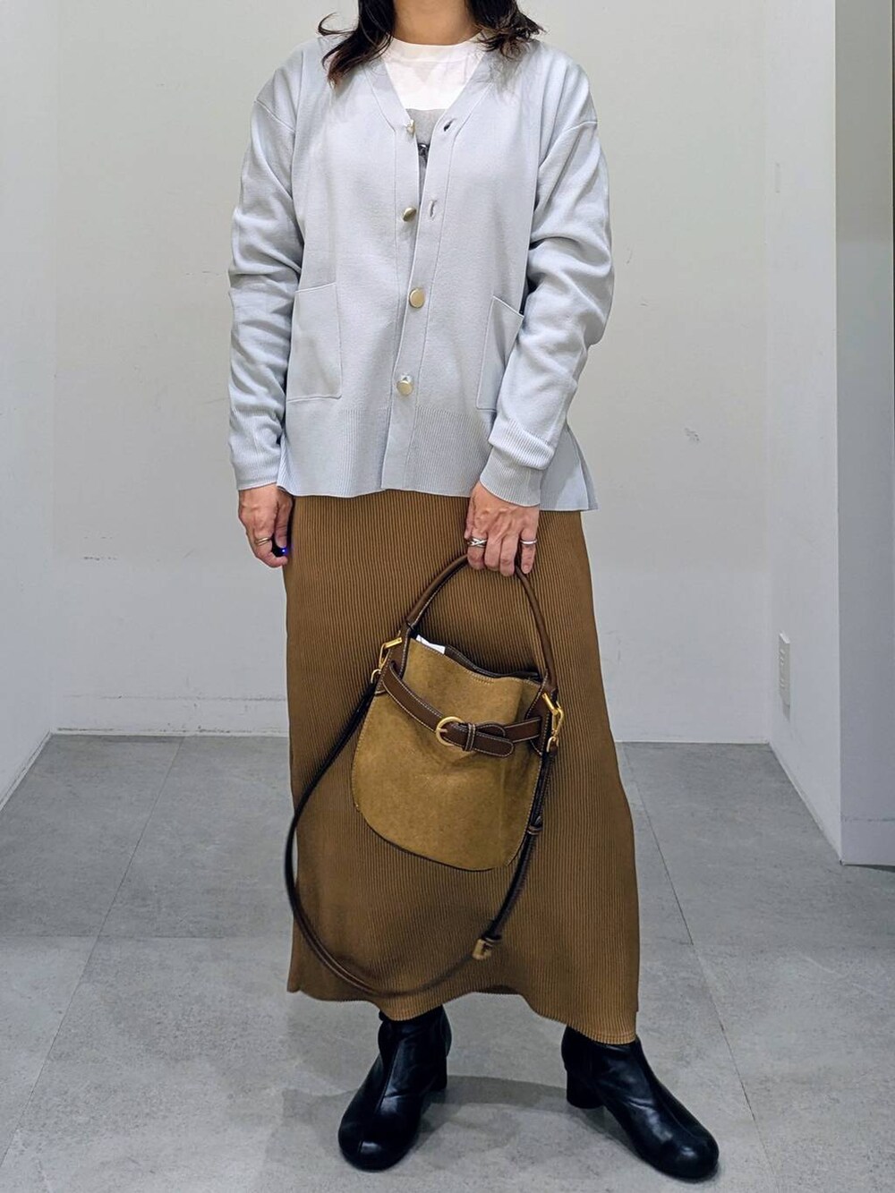 グレー系のカーディガン/ボレロ、ホワイト系のTシャツ/カットソー、ブラック系のブーツを着用したレディースの秋コーディネートの6枚目の写真