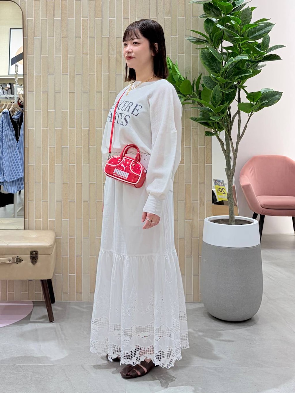 レッド系のハンドバッグ、ブラウン系のパンプス、ホワイト系のスカートを着用したレディースの春コーディネートの3枚目の写真