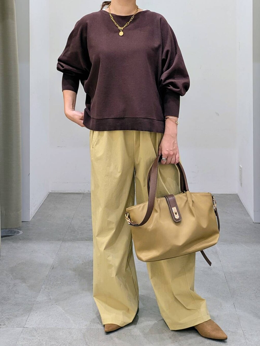 ブラウン系のパンプス、ベージュ系のハンドバッグ、ブラウン系のニット/セーターを着用したレディースの秋コーディネートの6枚目の写真