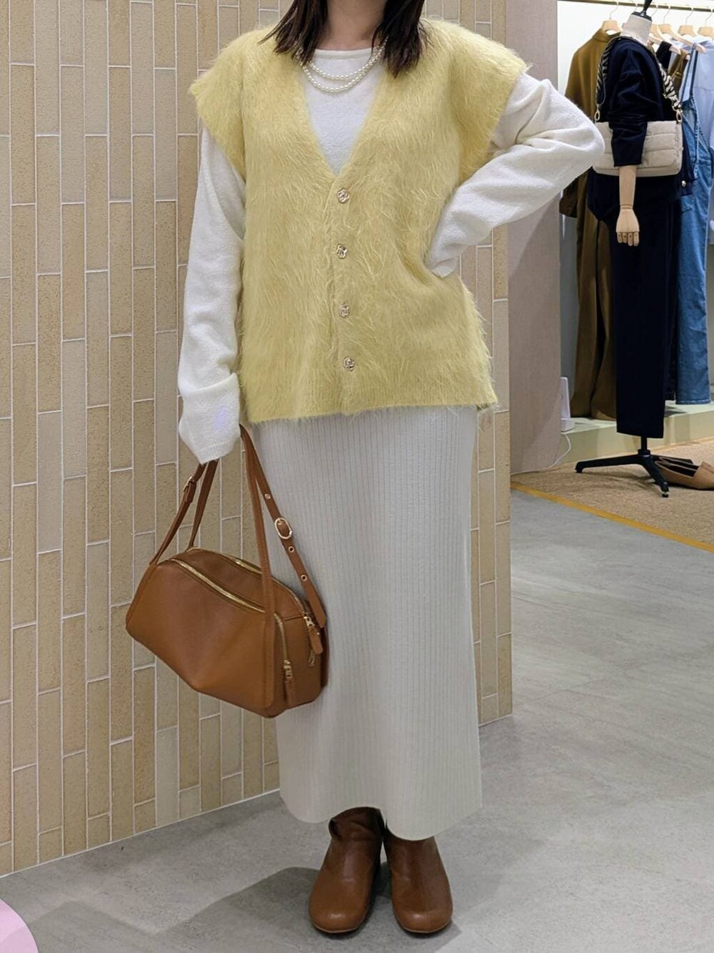 ベージュ系のスカート、ブラウン系のブーツ、ブラウン系のショルダーバッグを着用したレディースの秋コーディネートの6枚目の写真