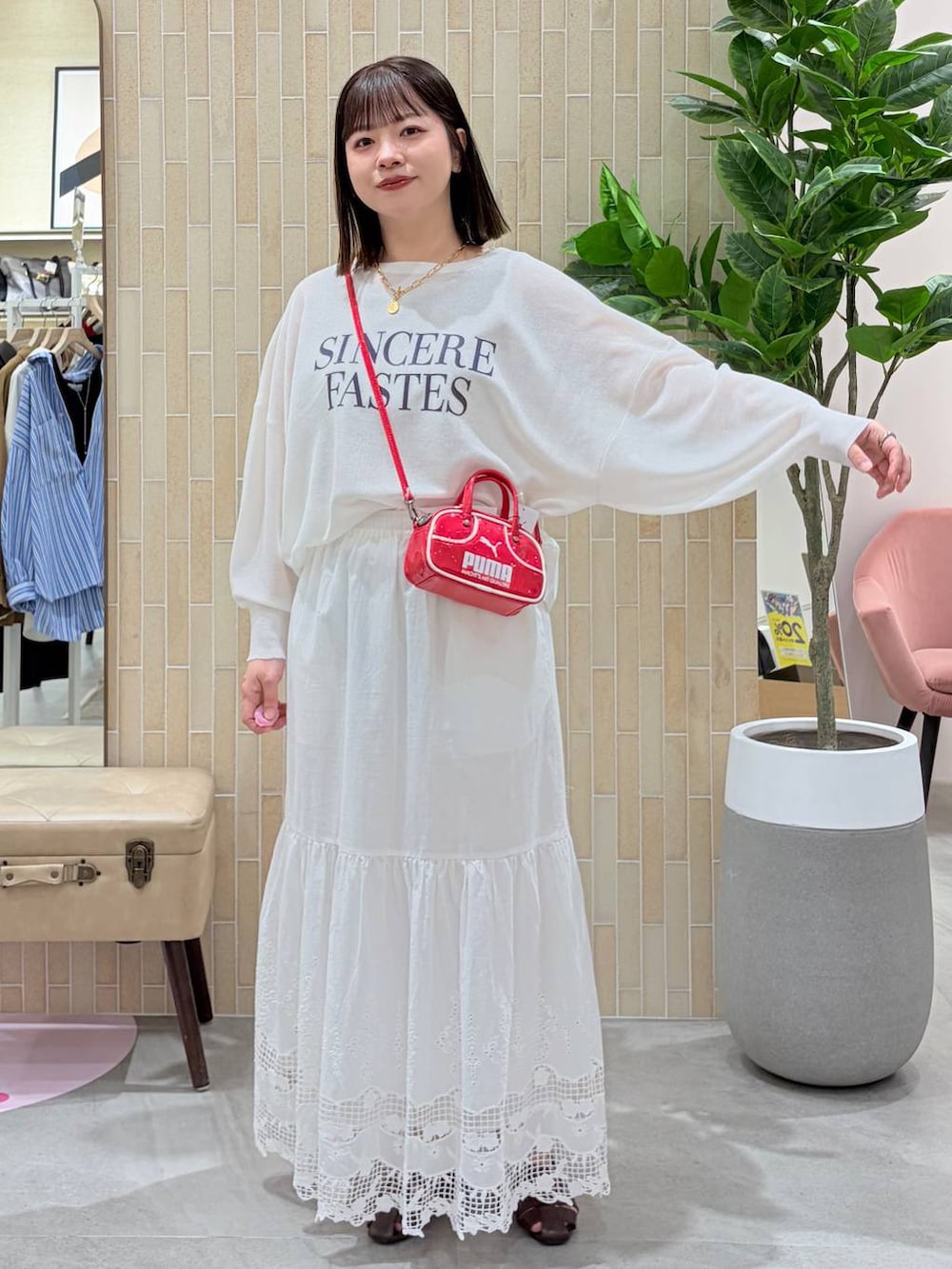 レッド系のハンドバッグ、ブラウン系のパンプス、ホワイト系のスカートを着用したレディースの春コーディネートの2枚目の写真