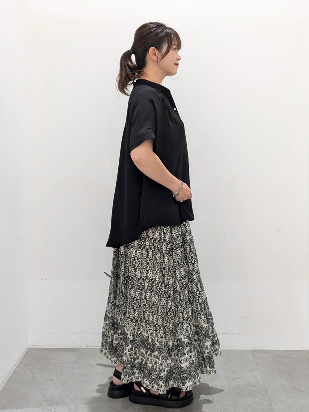 ブラック系のスカート、ブラック系のサンダル、ブラック系のTシャツ/カットソーを着用したレディースの夏コーディネートの6枚目の写真