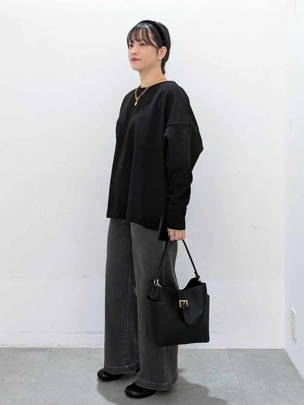 ブラック系のブーツ、ブラック系のショルダーバッグ、ブラック系のデニムパンツを着用したレディースの秋コーディネートの3枚目の写真