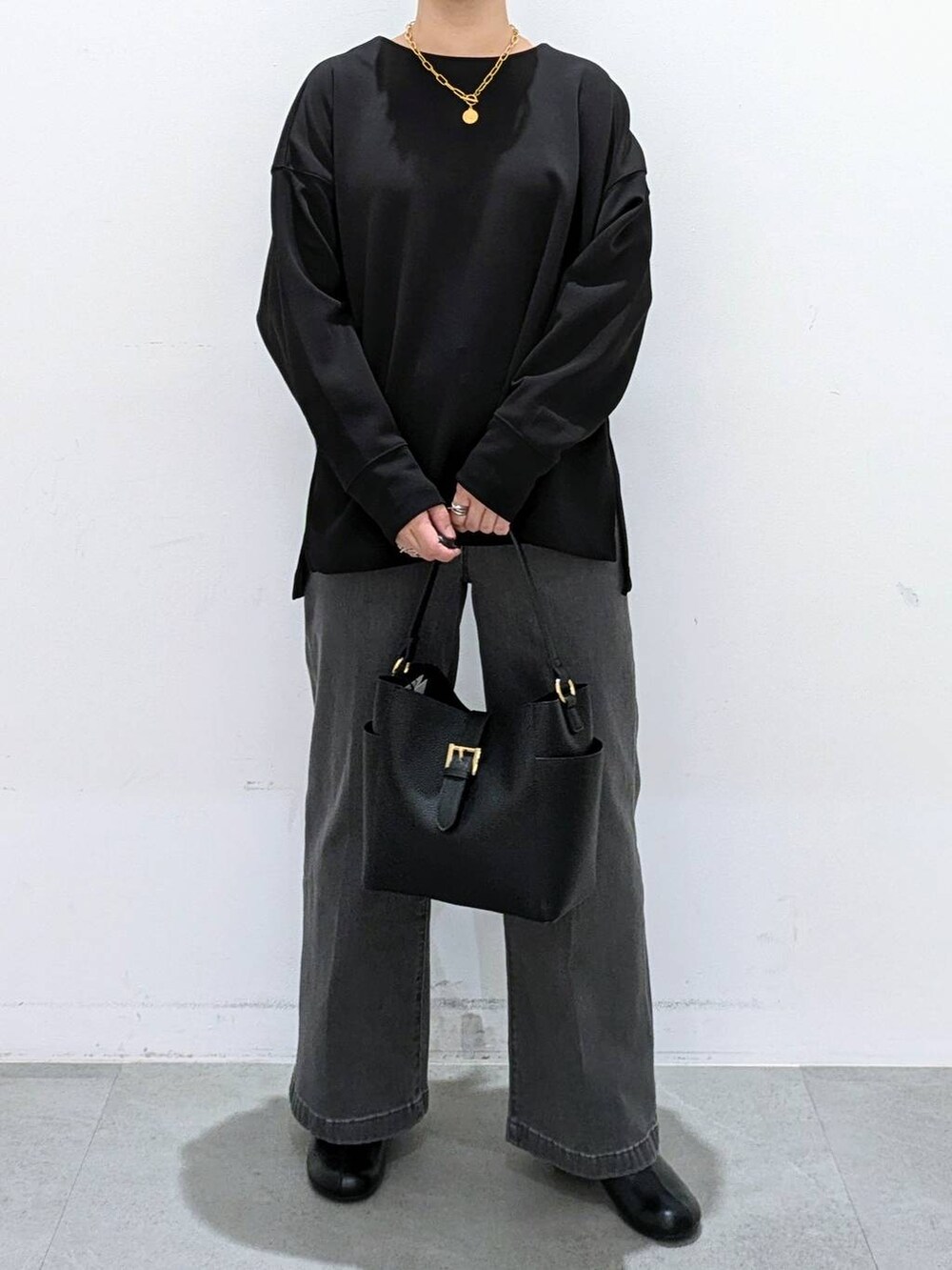 ブラック系のブーツ、ブラック系のショルダーバッグ、ブラック系のデニムパンツを着用したレディースの秋コーディネートの6枚目の写真