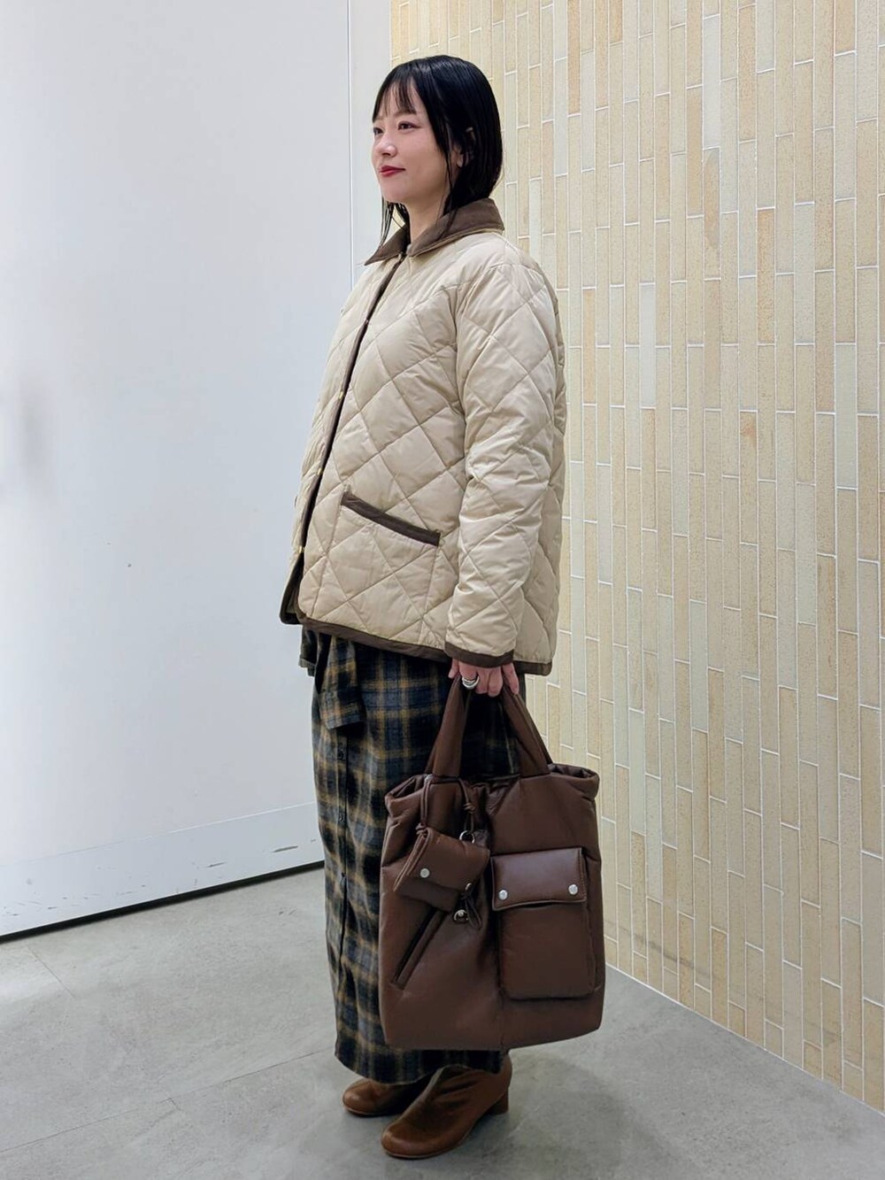 ブラウン系のブーツ、ベージュ系のダウンジャケット/コート、イエロー系のスカートを着用したレディースの冬コーディネートの3枚目の写真