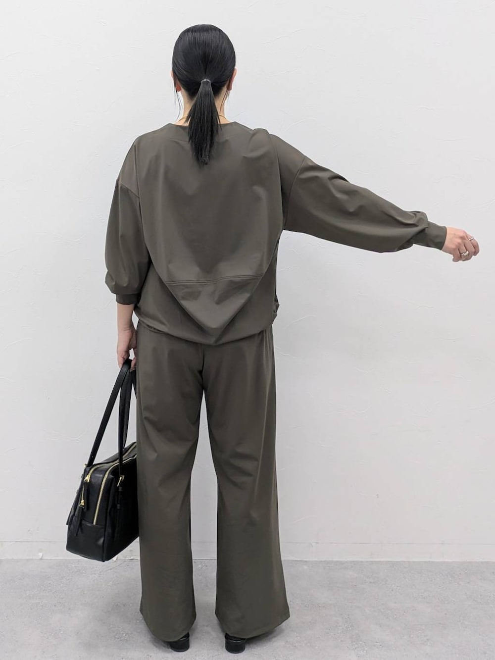 ブラック系のボストンバッグ、ブラック系のパンプス、グリーン系のその他パンツを着用したレディースの冬コーディネートの4枚目の写真