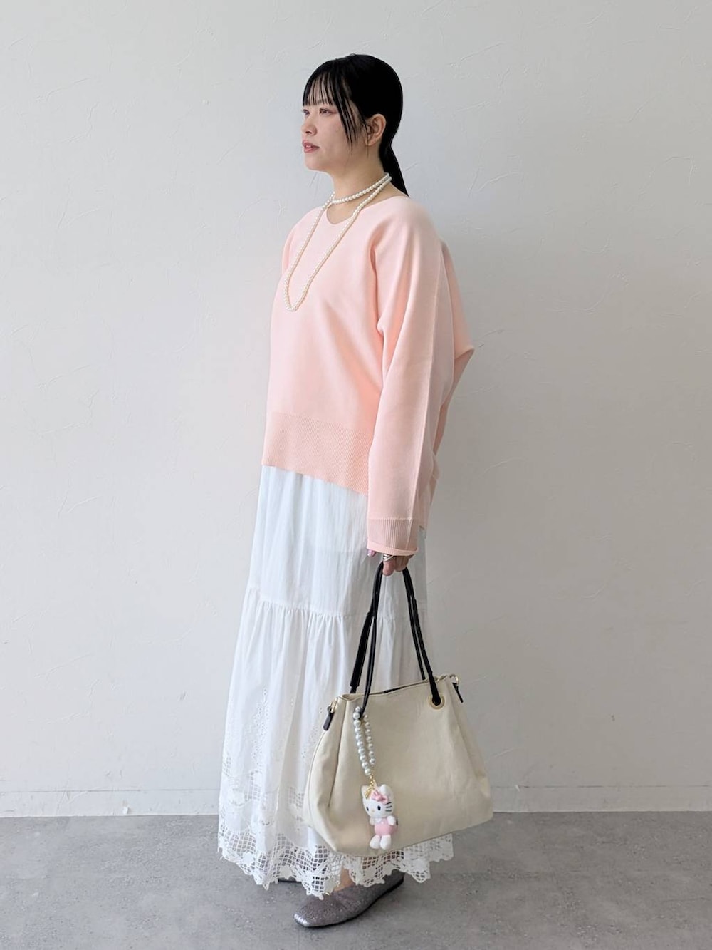 ホワイト系のトートバッグ、ピンク系のニット/セーター、ホワイト系のスカートを着用したレディースの春コーディネートの3枚目の写真