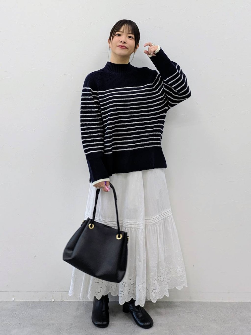 ブラック系のブーツ、ブルー系のニット/セーター、ホワイト系のスカートを着用したレディースの冬コーディネートの2枚目の写真