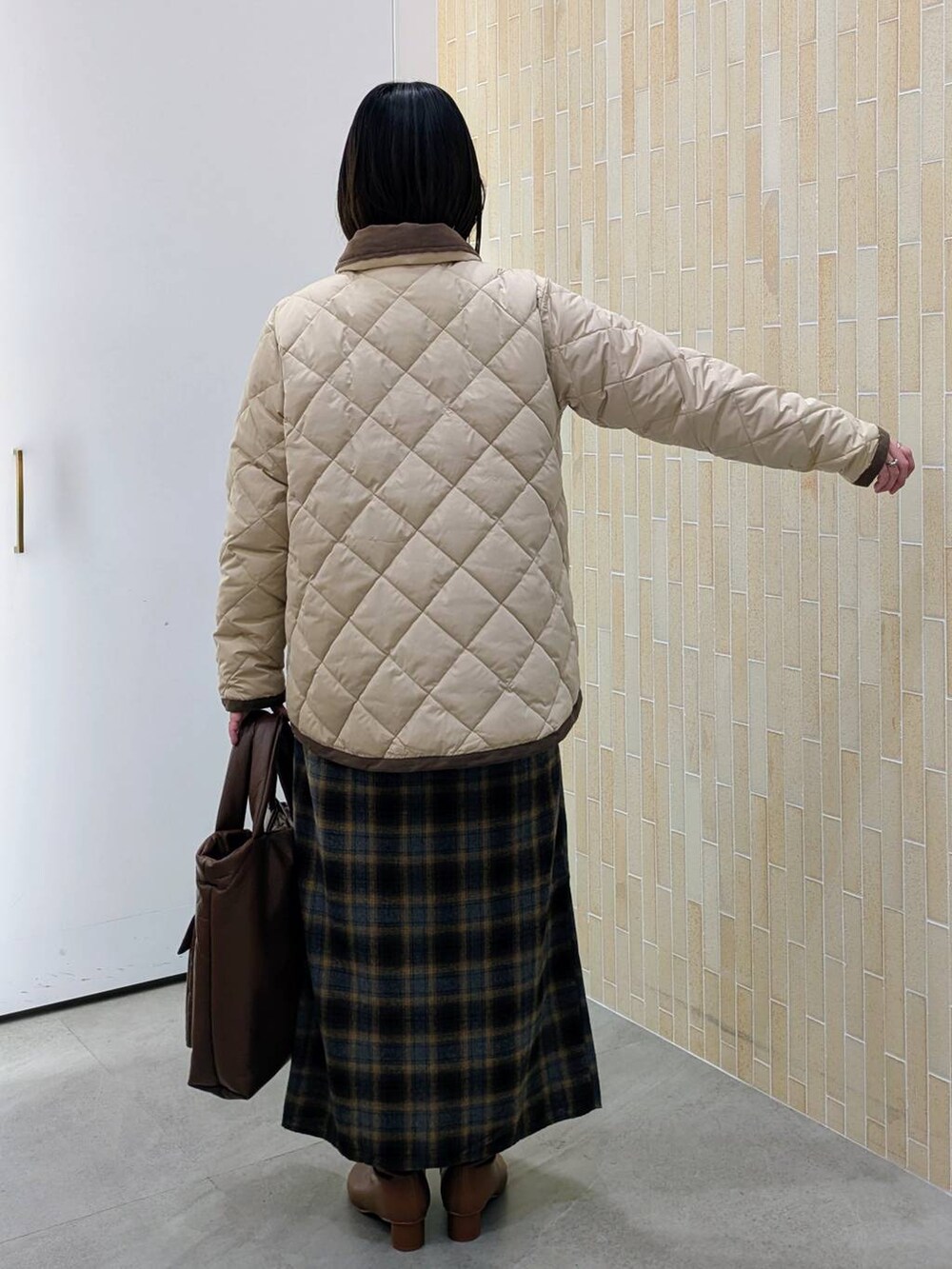 ブラウン系のブーツ、ベージュ系のダウンジャケット/コート、イエロー系のスカートを着用したレディースの冬コーディネートの4枚目の写真