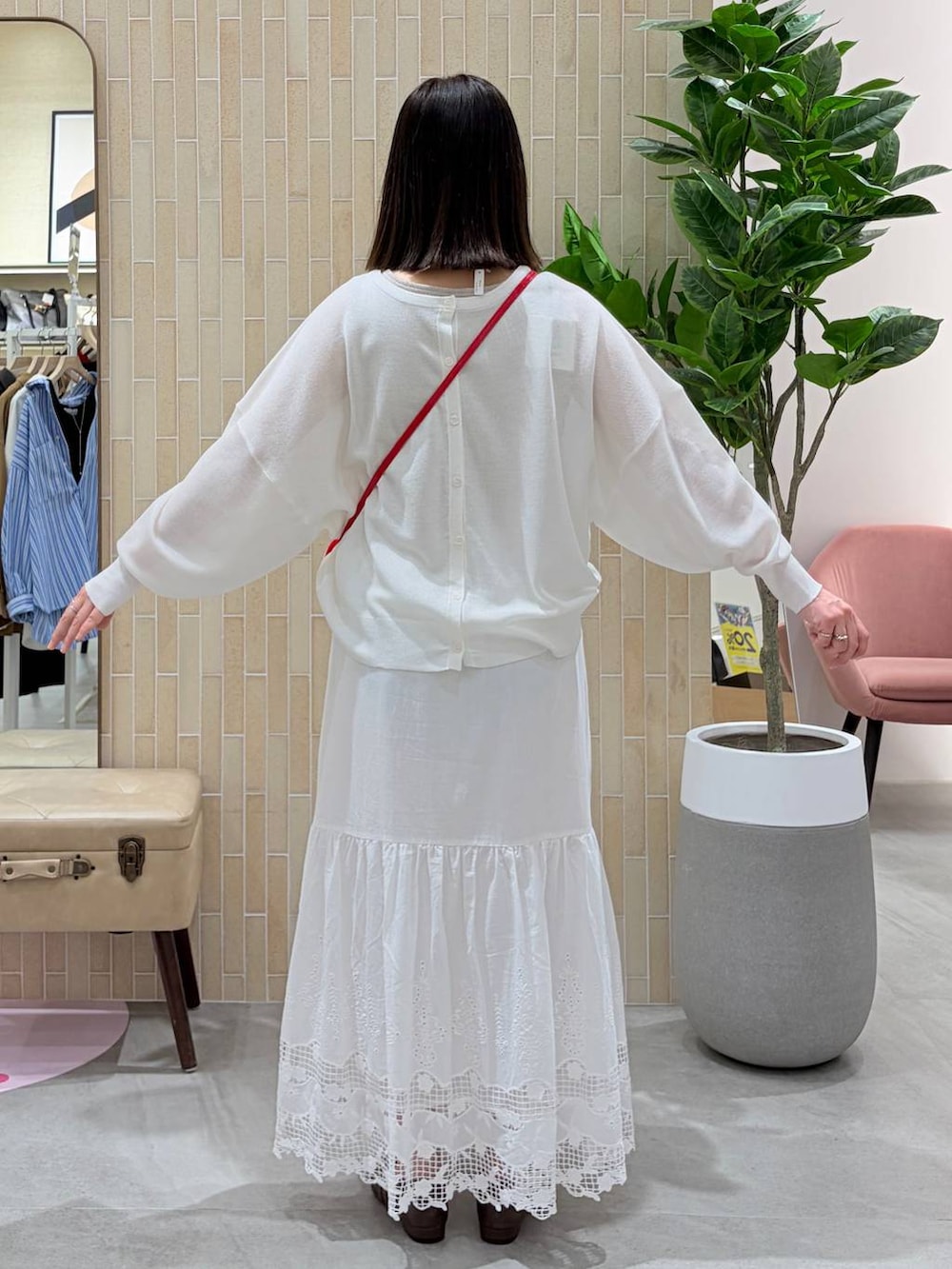 レッド系のハンドバッグ、ブラウン系のパンプス、ホワイト系のスカートを着用したレディースの春コーディネートの4枚目の写真