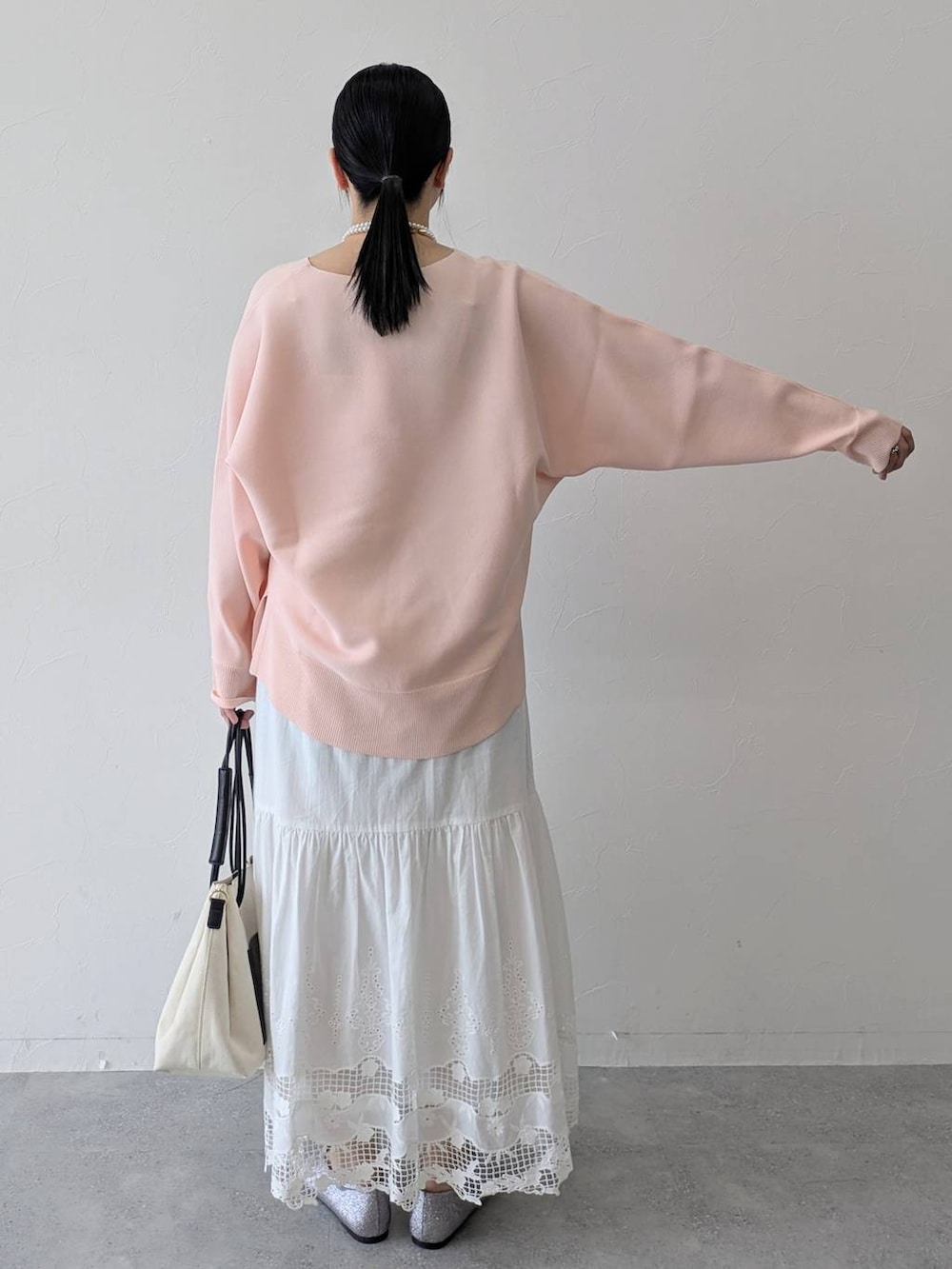 ホワイト系のトートバッグ、ピンク系のニット/セーター、ホワイト系のスカートを着用したレディースの春コーディネートの4枚目の写真