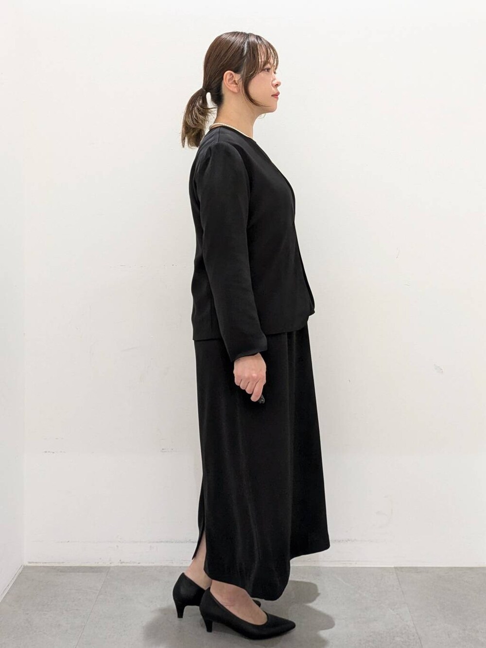 ブラック系のスーツジャケット、ブラック系のワンピース、ブラック系のパンプスを着用したレディースの春コーディネートの5枚目の写真