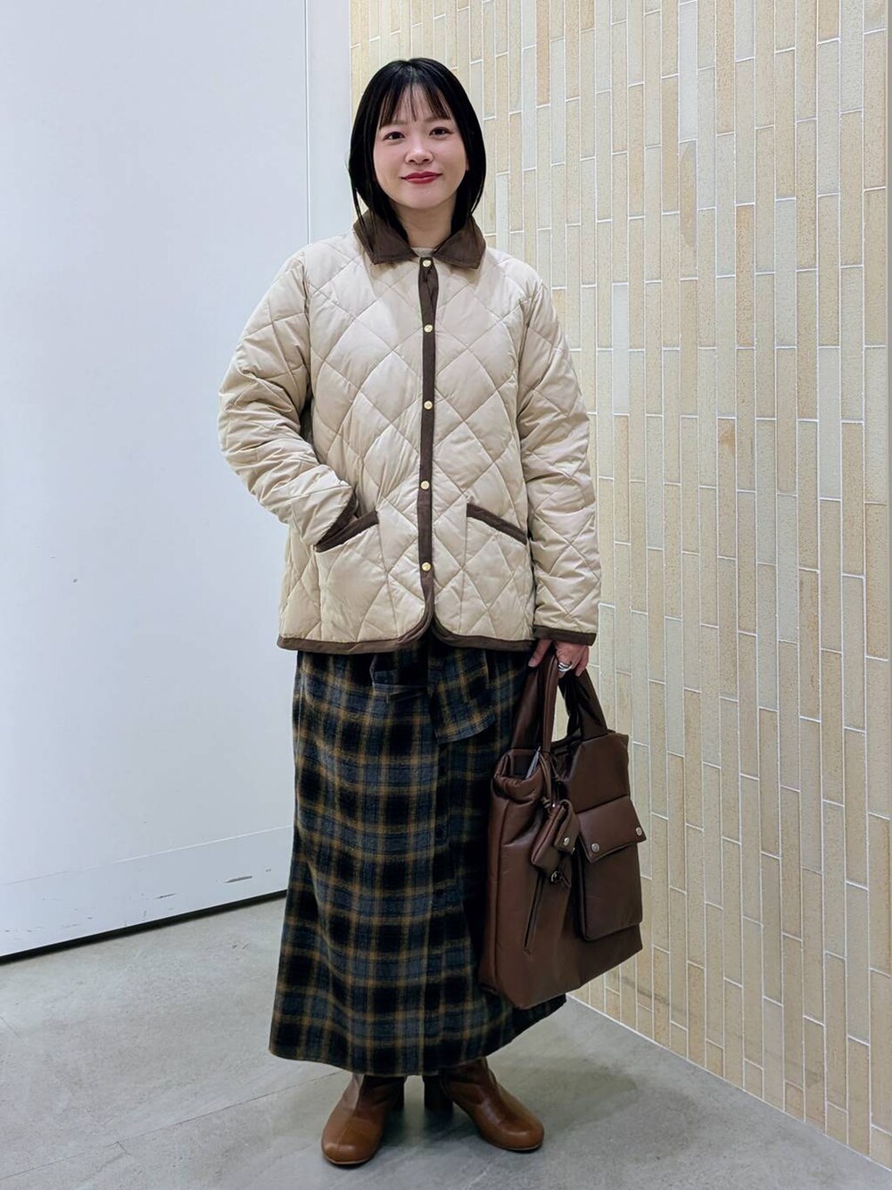 ブラウン系のブーツ、ベージュ系のダウンジャケット/コート、イエロー系のスカートを着用したレディースの冬コーディネートの2枚目の写真