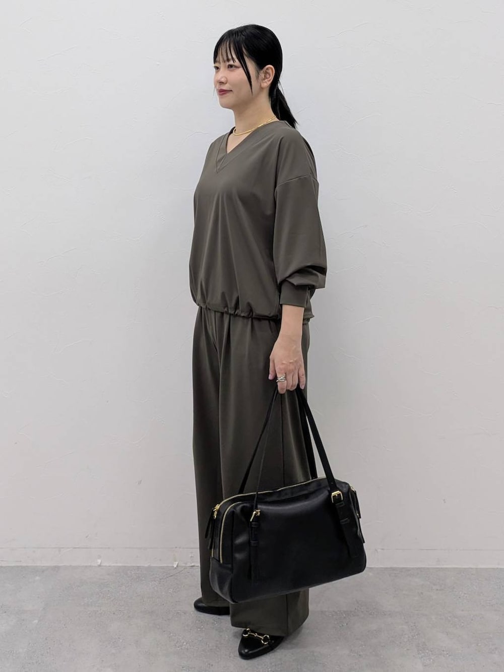 ブラック系のボストンバッグ、ブラック系のパンプス、グリーン系のその他パンツを着用したレディースの冬コーディネートの3枚目の写真