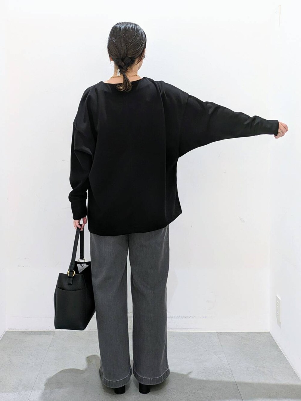 ブラック系のブーツ、ブラック系のショルダーバッグ、ブラック系のデニムパンツを着用したレディースの秋コーディネートの4枚目の写真