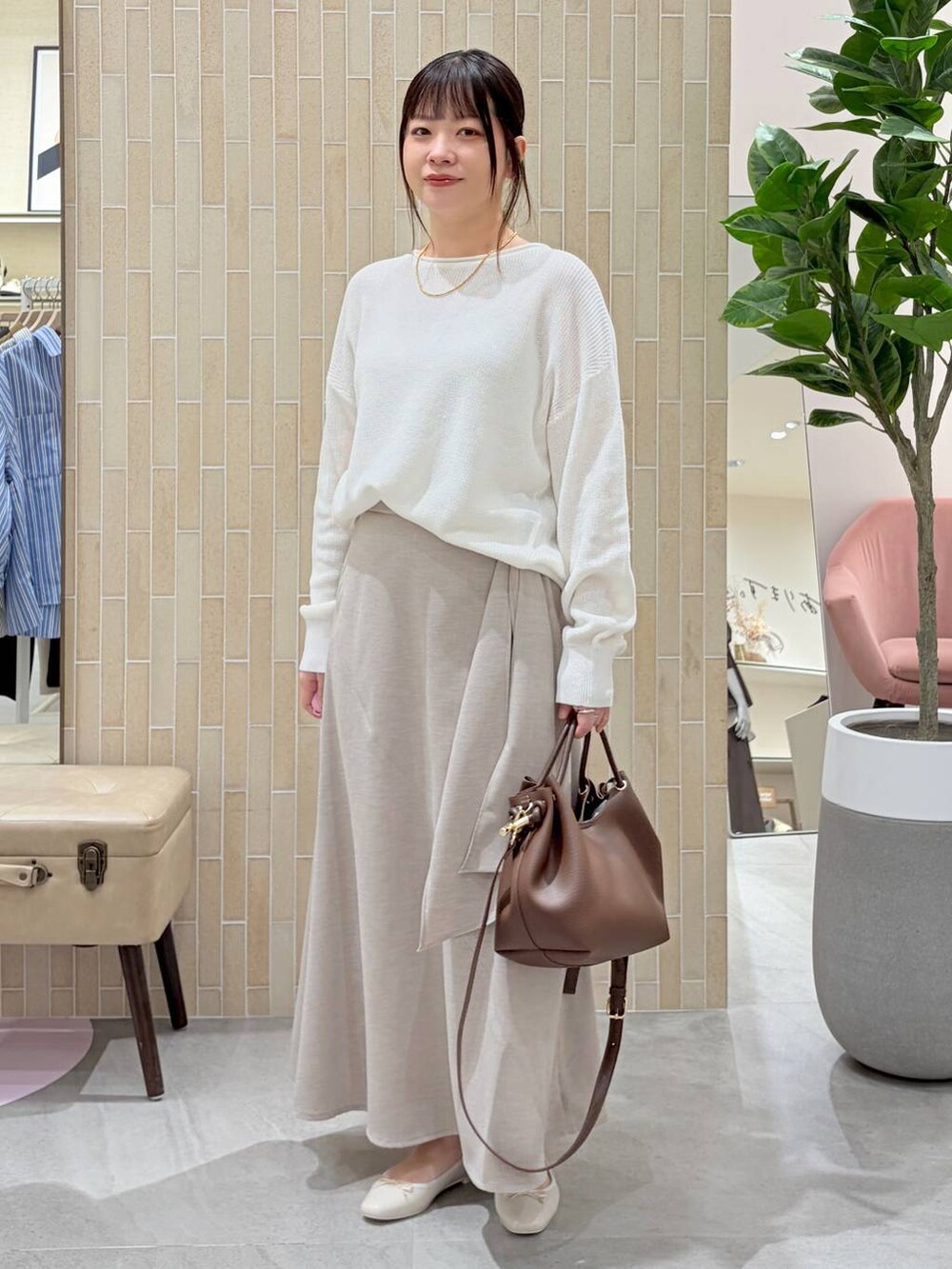 ホワイト系のニット/セーター、ブラウン系のハンドバッグ、ベージュ系のスカートを着用したレディースの春コーディネートの2枚目の写真