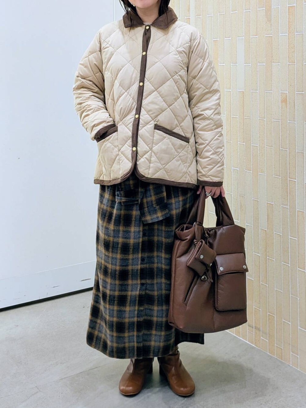 ブラウン系のブーツ、ベージュ系のダウンジャケット/コート、イエロー系のスカートを着用したレディースの冬コーディネートの6枚目の写真