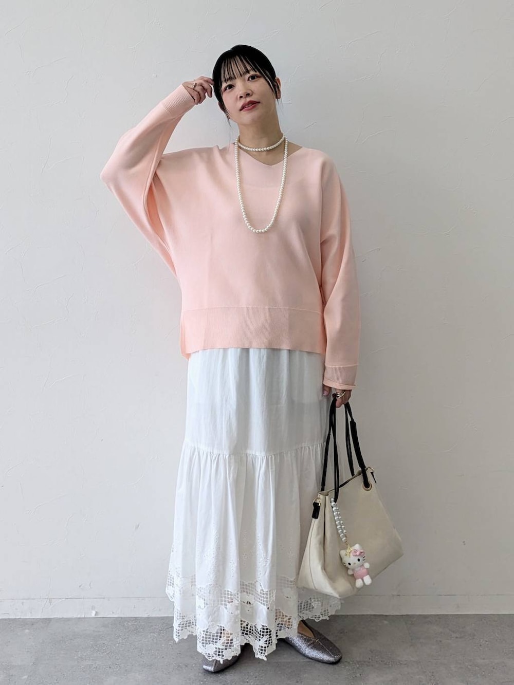 ホワイト系のトートバッグ、ピンク系のニット/セーター、ホワイト系のスカートを着用したレディースの春コーディネートの2枚目の写真