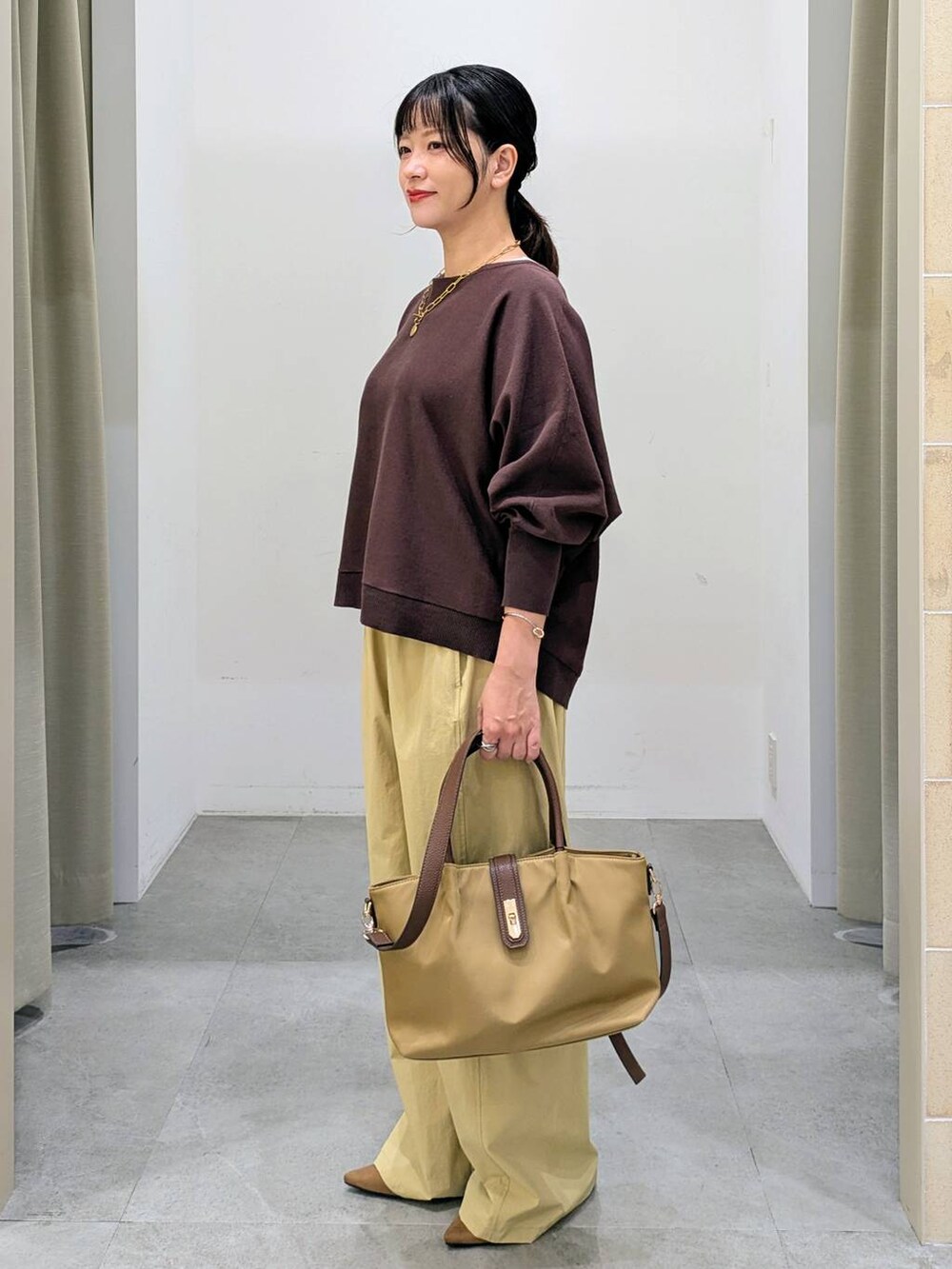 ブラウン系のパンプス、ベージュ系のハンドバッグ、ブラウン系のニット/セーターを着用したレディースの秋コーディネートの3枚目の写真